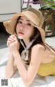 A woman wearing a straw hat laying on a bed.