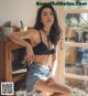 A woman in a black bra top and denim shorts posing for a picture.