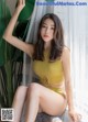 A woman in a yellow top and yellow panties sitting on a chair.