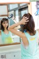 A woman blow drying her hair in front of a mirror.