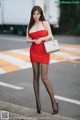 A woman in a red dress is walking down the street.