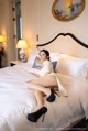 A woman sitting on a bed in a hotel room.