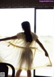 A woman in a yellow dress standing in front of a window.