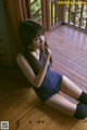 A woman sitting on a wooden floor next to a window.