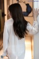 A woman in a white shirt leaning against a wall.