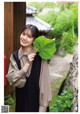 A woman holding a large green leaf in her hand.