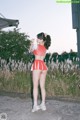 A woman in a red and white cheerleading uniform standing in a field.