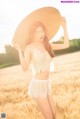 A woman in a straw hat standing in a field.