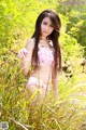 A woman in a pink bikini standing in tall grass.