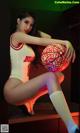 A woman in a white bodysuit holding a basketball.