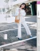 A woman in a white shirt and white pants is posing for a magazine.