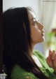 A woman with long black hair looking out a window.