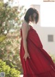 A woman in a red dress standing in front of a building.