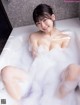 A woman is sitting in a bathtub filled with foam.