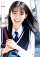 A young woman in a school uniform smiles at the camera.