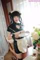 A woman in a maid outfit holding a tray of food.