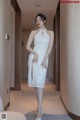 A woman in a white dress standing in a hallway.