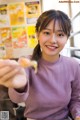 A woman holding a piece of food in her hand.