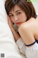 A woman laying on top of a bed next to a pillow.