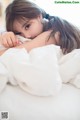 A young woman laying in bed with her head on the pillow.