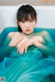 A woman in a blue dress sitting in a bathtub.