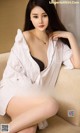 A woman sitting on top of a couch wearing a white shirt.