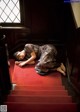 A woman laying on a red carpeted stairway next to a window.