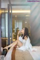 A woman sitting on a bed in a hotel room.