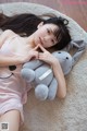 A woman laying on the floor with a stuffed animal.