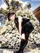 A woman with a backpack standing in front of a bush.