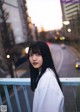 A woman with long black hair standing on a bridge.