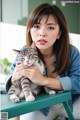 A woman sitting at a table holding a cat.