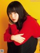 A woman in a red sweater and black skirt posing for a picture.