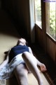 A woman laying on the floor in front of a window.