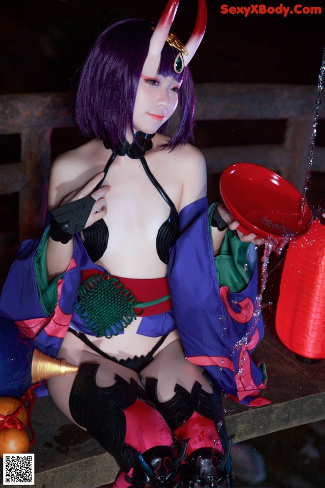 A woman dressed as a demon holding a red bowl.